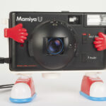 The camera slides into the little gloved hands and stands on two feet. Like, a crazy plastic tripod. WOW!